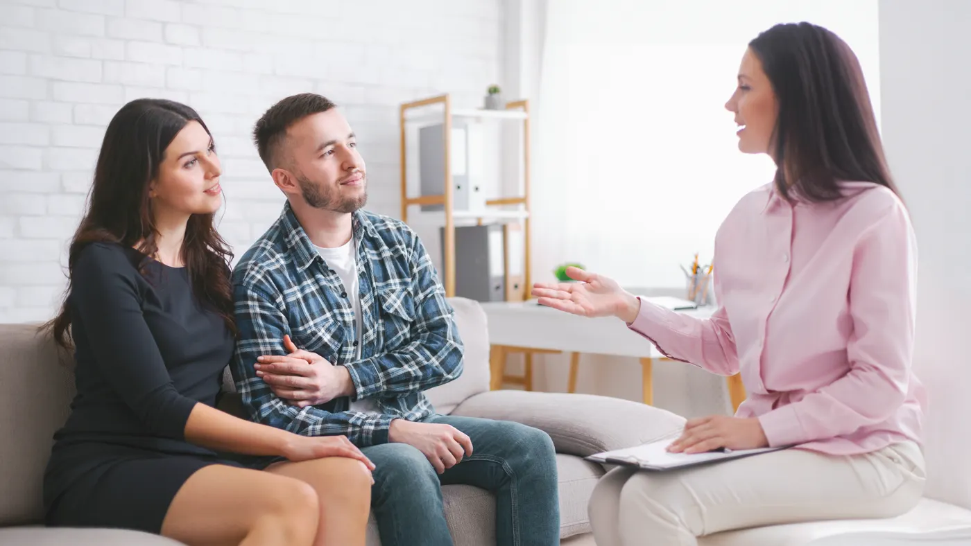Casal sentado no sofá conversando com uma psicóloga